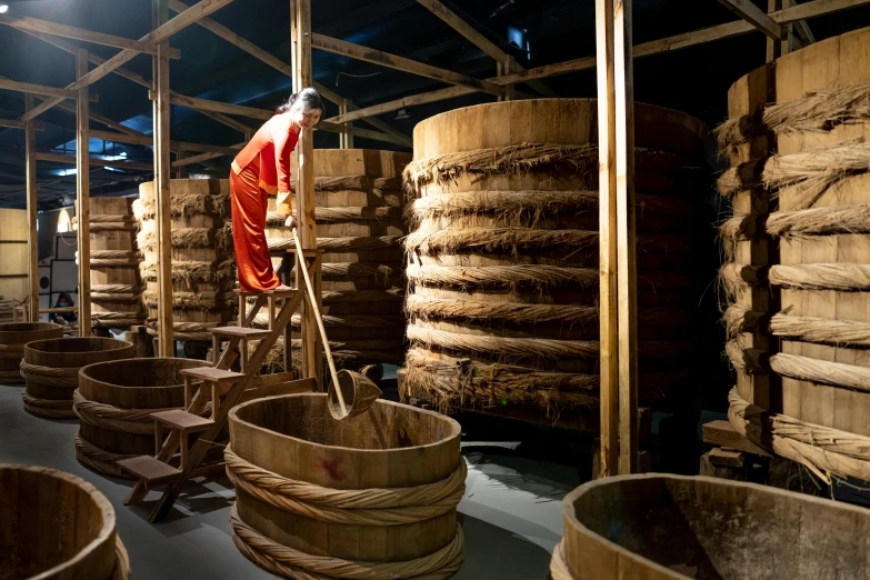 a man standing on a ladder in a room filled with wooden barrels, inspired by Li Di, process art, hanfu, réunion des musées nationaux, avatar image, rice