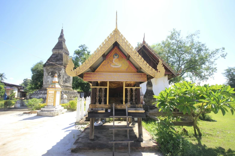 a small wooden building sitting on top of a lush green field, thai temple, shiny gold, youtube thumbnail, square