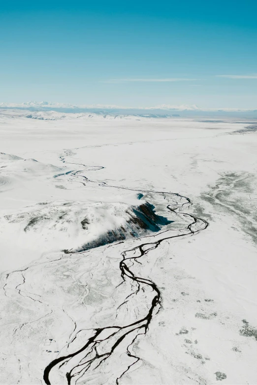 an aerial view of a river in the snow, black volcano afar, mountains of ice cream, wind river valley, explore