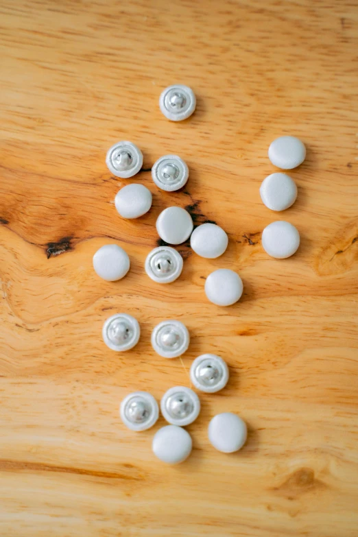 a bunch of white knobs sitting on top of a wooden table, a picture, by Ottó Baditz, unsplash, hero shot, jewel embellishment, 10mm, back