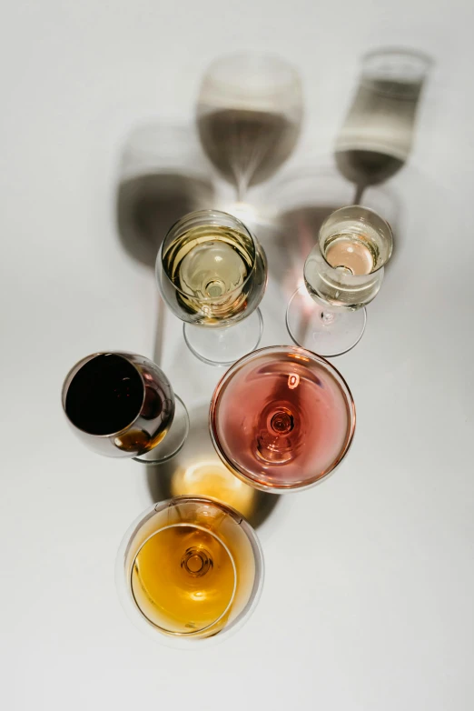 a group of wine glasses sitting on top of a table, a still life, by Jan Rustem, unsplash, show from below, high angle close up shot, deconstructed, various colors