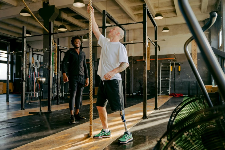 a man holding onto a rope in a gym, by Meredith Dillman, hurufiyya, one legged amputee, pete davidson, holding a wooden staff, high quality upload