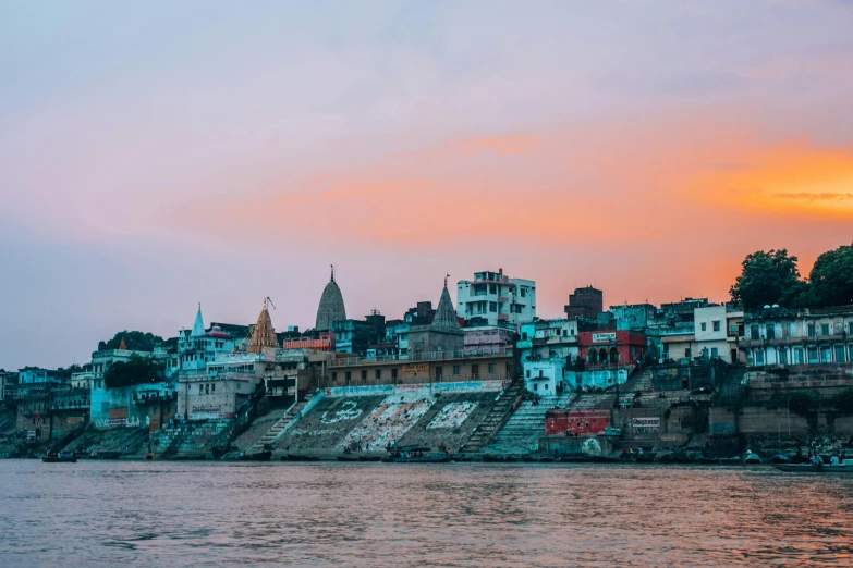 a group of buildings sitting on the side of a river, pexels contest winner, hindu aesthetic, faded glow, multicoloured, view from the sea