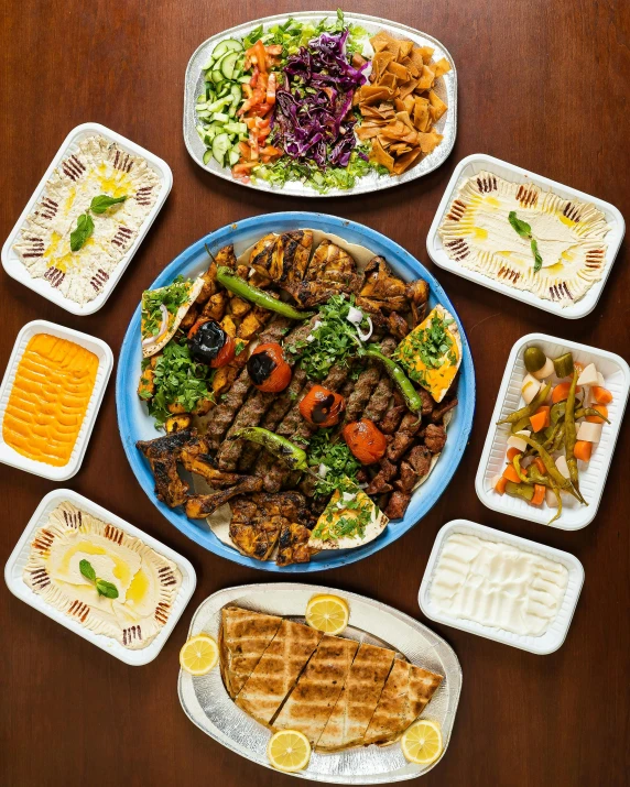 a wooden table topped with plates of food, dau-al-set, profile image, group photo, grill, top - view