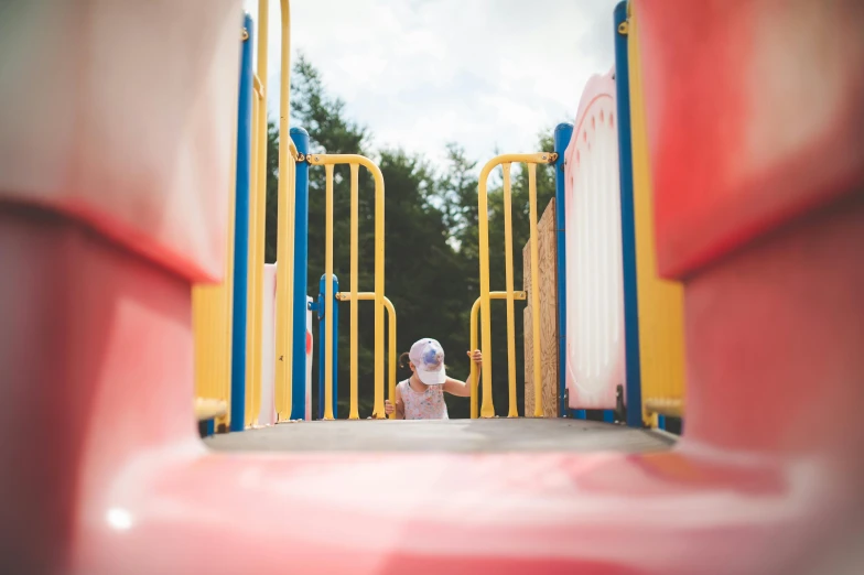 a toddler playing on a slide at a park, by Arabella Rankin, pexels contest winner, square, complex background, hiding behind obstacles, coloured photo