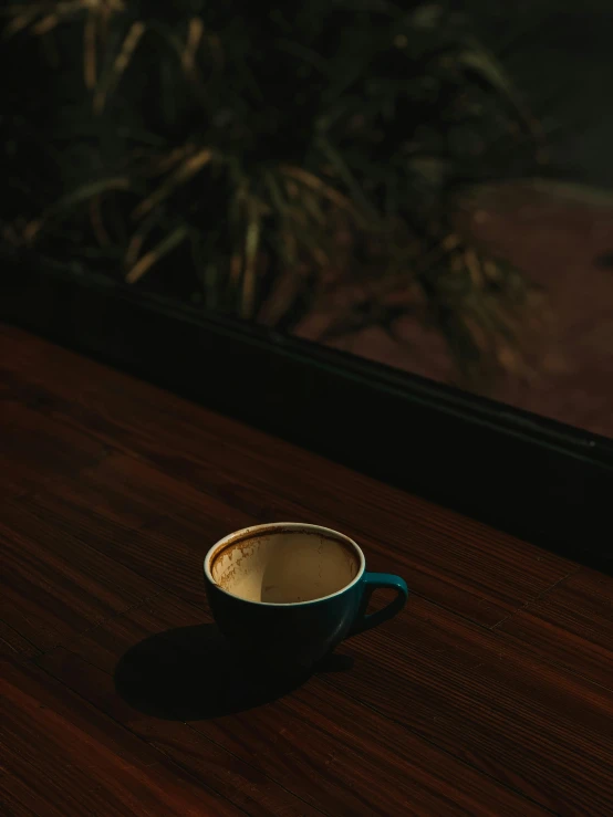 a cup of coffee sitting on top of a wooden table, inspired by Elsa Bleda, dark. no text, instagram post, window open, underexposed