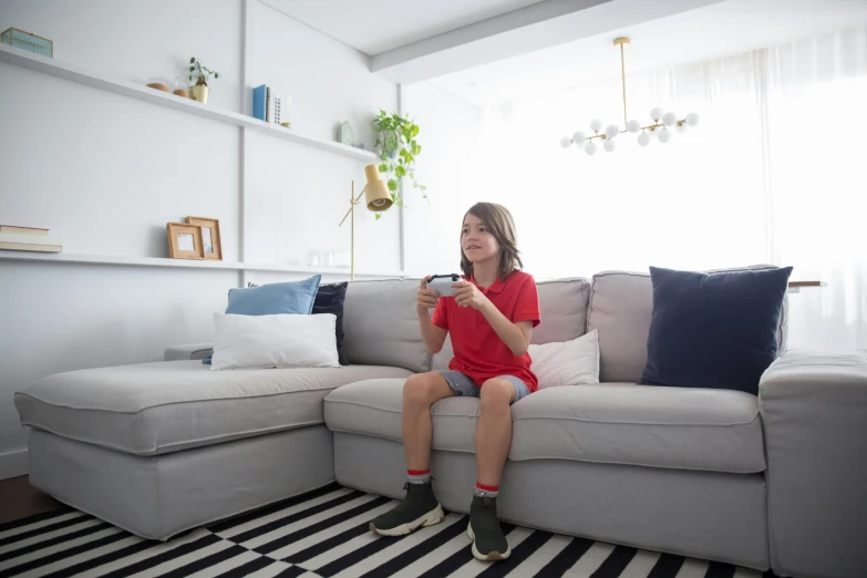 a little girl sitting on a couch playing a video game, pexels contest winner, ikea, soft grey and red natural light, boy's room, avatar image