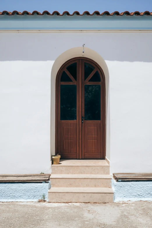 a red fire hydrant sitting in front of a white building, inspired by Riad Beyrouti, unsplash, minimalism, arched doorway, a wooden, swimming pool in front, architectural digest