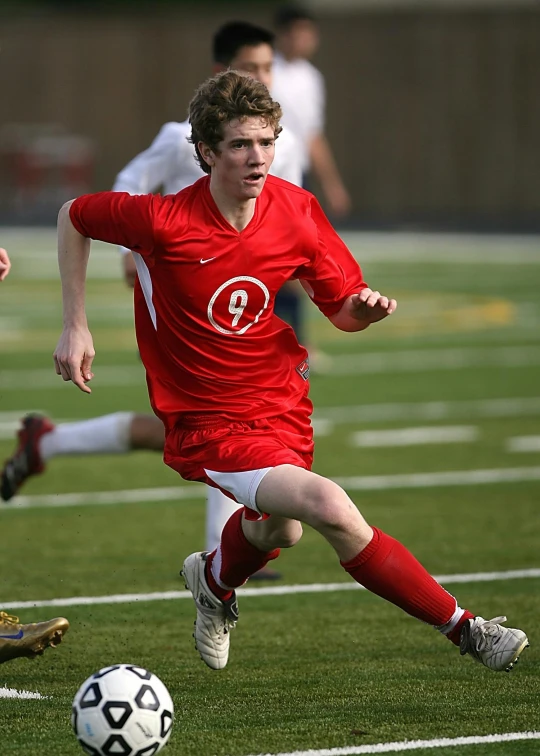 a group of young men playing a game of soccer, photo of mark zuckerberg, wearing a red captain's uniform, running, taken in the late 2010s