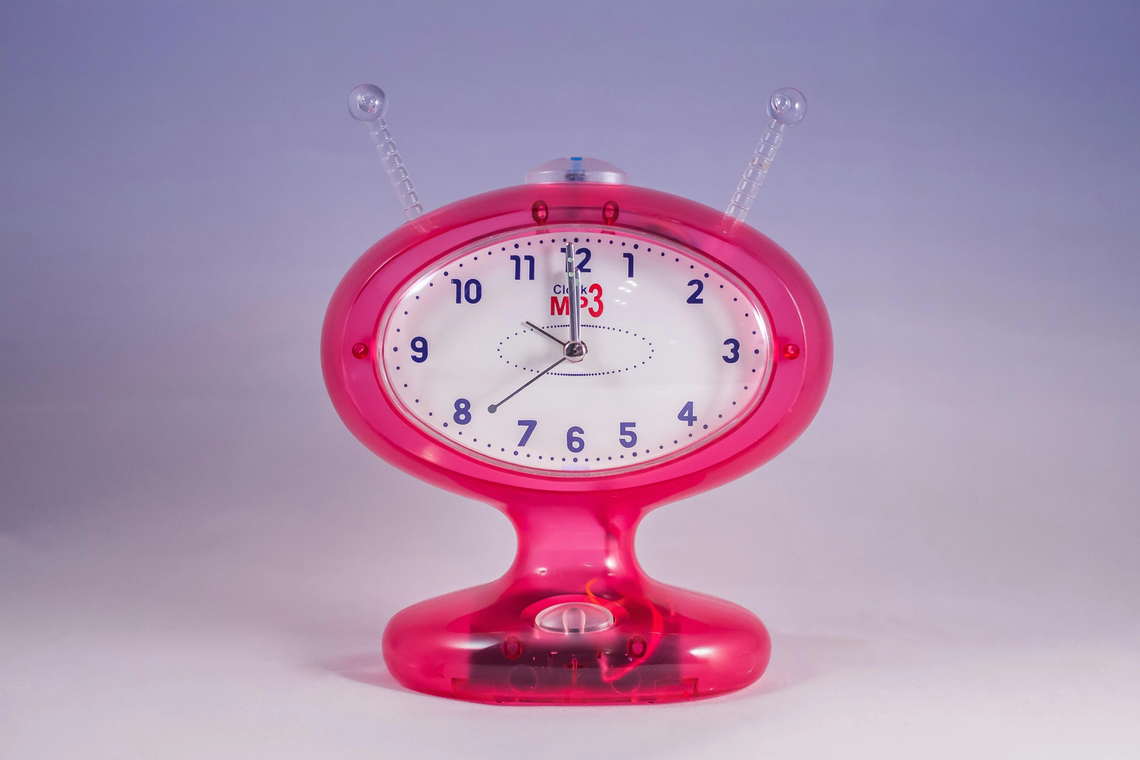 a pink clock sitting on top of a table, kitsch movement, martian, mtv, made out of clear plastic, early 2 0 0 0 s