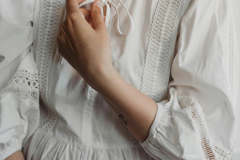 a close up of a person wearing a white dress, a tattoo, by Emma Andijewska, trending on pexels, aestheticism, white poet shirt, cottagecore, arm tattoo, muted colour