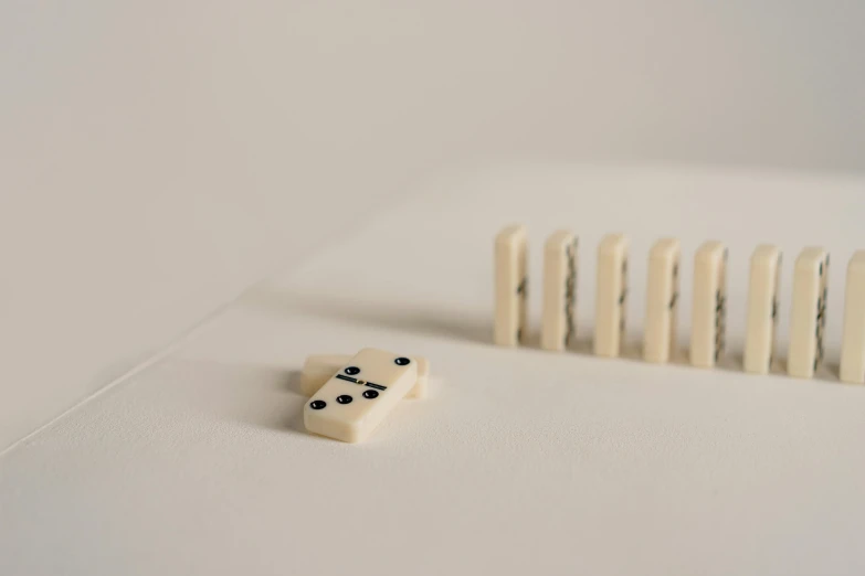 a group of dominos sitting on top of a white surface, a macro photograph, by Emma Andijewska, visual art, cross composition, threes, 2022 photograph, game