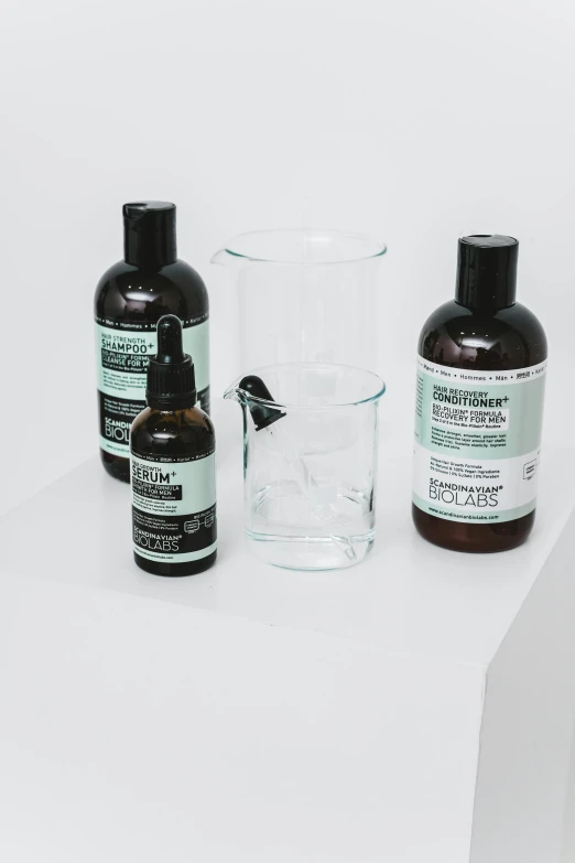 a couple of bottles of liquid sitting on top of a table, by Nina Hamnett, unsplash, visual art, skincare, black and green, medical labels, transparent glass vase