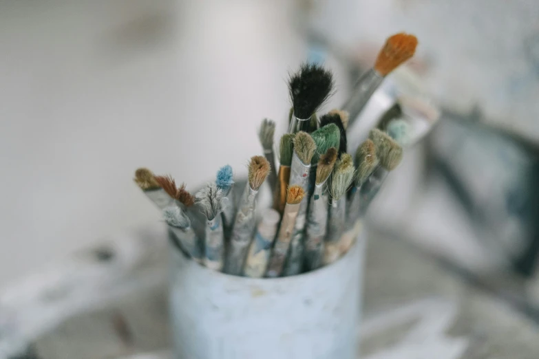 a cup full of paint brushes sitting on a table, trending on pexels, oil paint style, white wall coloured workshop, close - up photograph, intricate oils