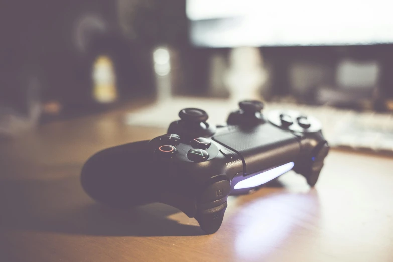 a video game controller sitting on top of a wooden table, by Carey Morris, unsplash, instagram post, playstation 3, avatar image, pixvy