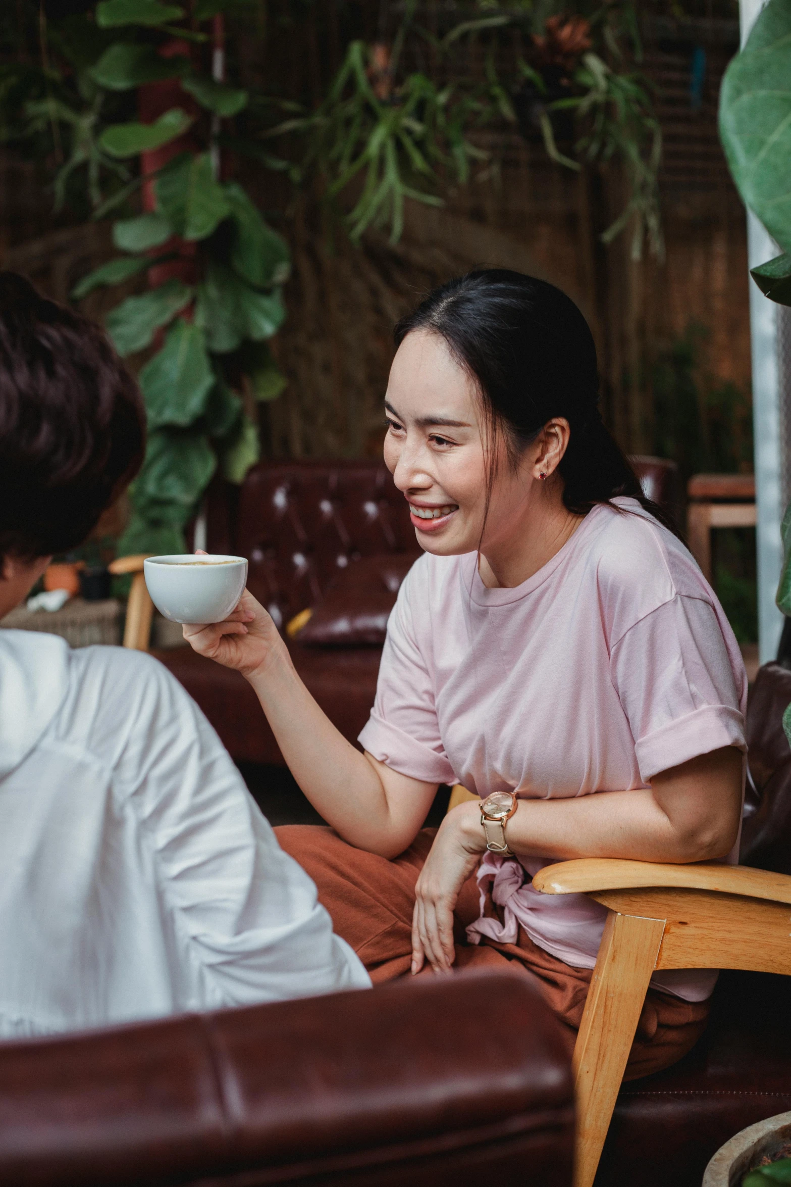 a couple of women sitting next to each other on a couch, inspired by Ruth Jên, pexels contest winner, happening, table in front with a cup, vietnamese woman, flirting smiling, outside