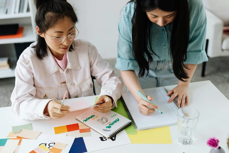 a woman and a young girl sitting at a table, a drawing, trending on pexels, design thinking, korean writing, 9 9 designs, college students