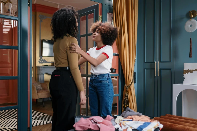 two women standing next to each other in a room, trending on pexels, happening, touching her clothes, with afro, france, supportive