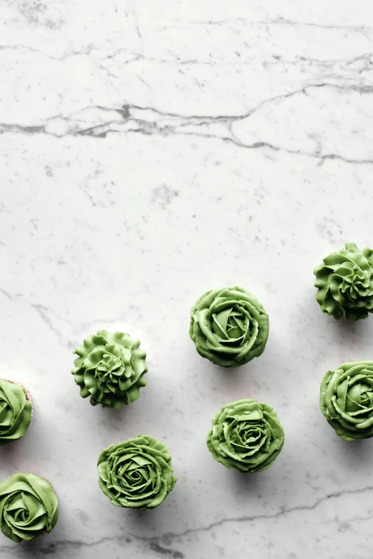 a table topped with cupcakes covered in green frosting, inspired by Art Green, trending on pexels, made of carrara marble, buds, 6 k, artichoke