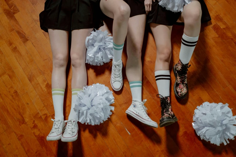 a group of young women sitting on top of a wooden floor, pexels, antipodeans, a teenage girl cheerleader, socks, white flowers on the floor, furry legs