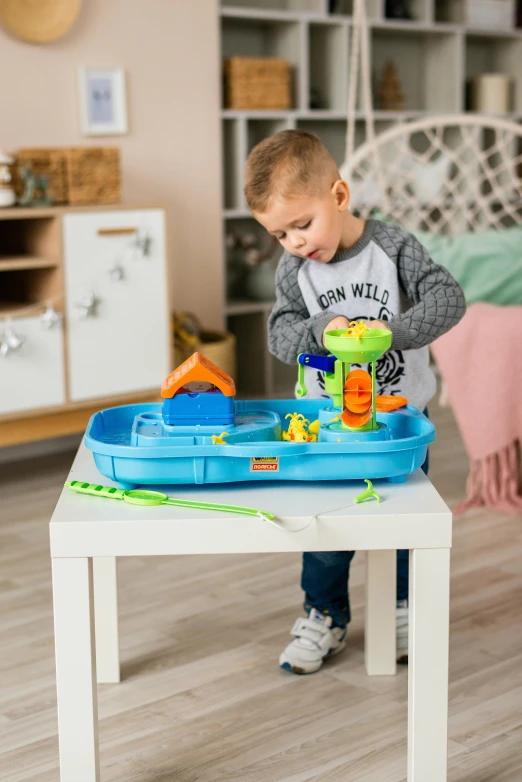 a little boy that is playing with a table, with a fishpond and courtyard, blippi, boat, mini model