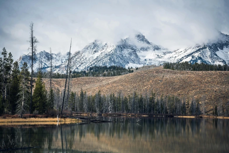 a lake with a mountain in the background, unsplash contest winner, hurufiyya, spring winter nature melted snow, wyoming, grey forest in the background, 2000s photo