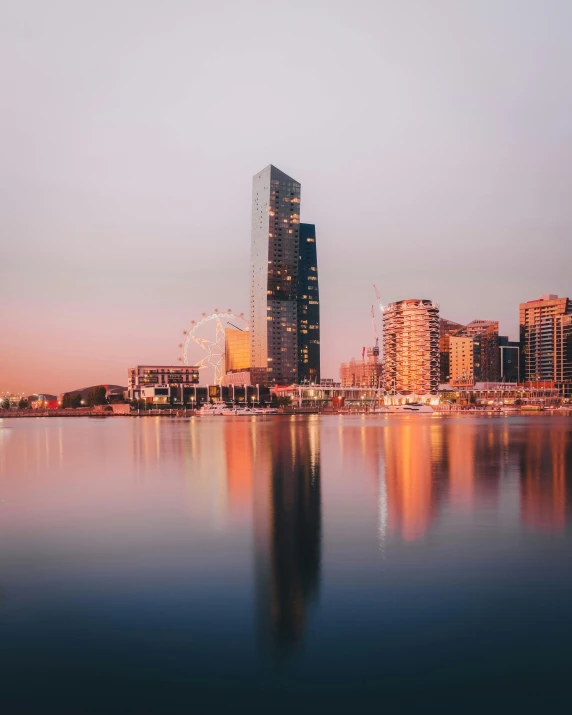 a large body of water with a city in the background, by Liza Donnelly, pexels contest winner, australian tonalism, pink golden hour, instagram story, glass buildings, standing upright