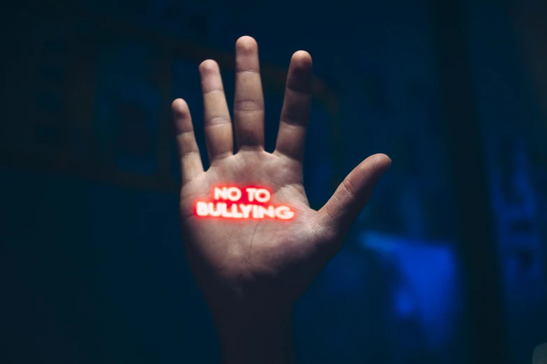 a hand with no to bullying written on it, a picture, by Adam Marczyński, blue and red lights, instagram picture, healthcare, adult