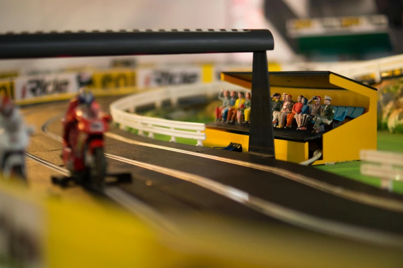 a miniature model of a race track with people on it, inspired by Brian Dunlop, pexels contest winner, yellow, detail on scene, toys, hand