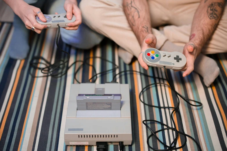 a couple of people sitting next to each other holding game controllers, pixel art, unsplash, neogeo, super nintendo cartridge, commodore 6 4, thumbnail, grey