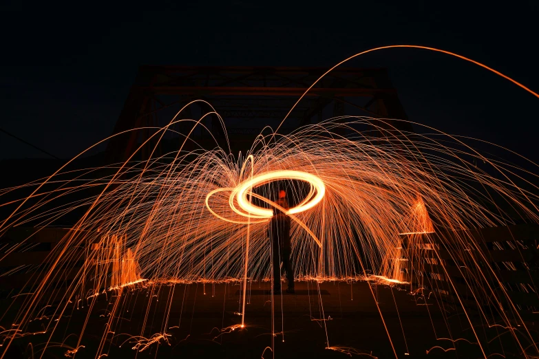 a man standing in front of a fire spinning in the air, by Sebastian Spreng, pexels contest winner, orange neon, metal works, outdoor photo, outline glow
