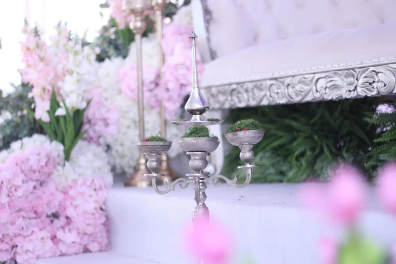 a silver candelab surrounded by pink and white flowers, by Itshak Holtz, unsplash, rococo, outdoors setting, egyptian setting, moss and flowers, wedding