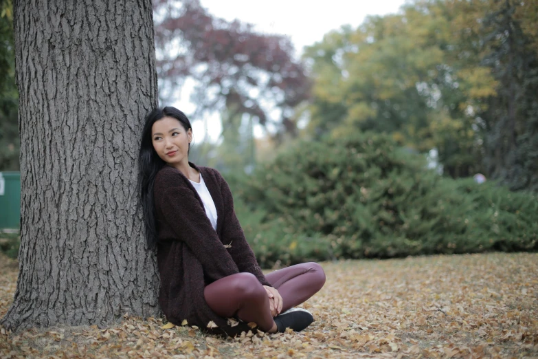 a woman sitting on the ground next to a tree, pexels contest winner, brown sweater, avatar image, asian female, close full body shot