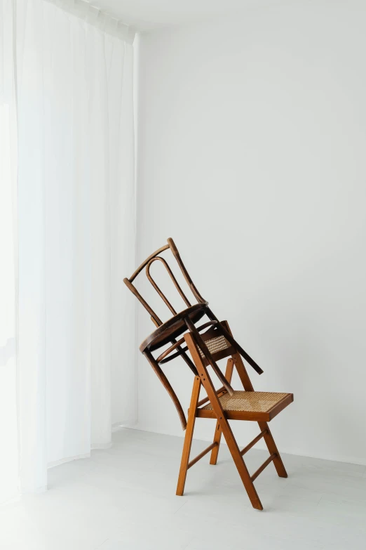 a wooden chair sitting in front of a window, inspired by Constantin Hansen, trending on unsplash, visual art, in front of white back drop, two hang, looking upward, folded