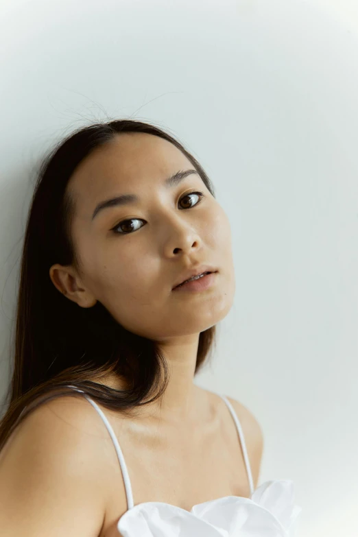 a woman in a white dress leaning against a wall, a character portrait, inspired by Kim Tschang Yeul, unsplash, hyperrealism, on grey background, relaxed eyebrows, ethnicity : japanese, mixed race woman