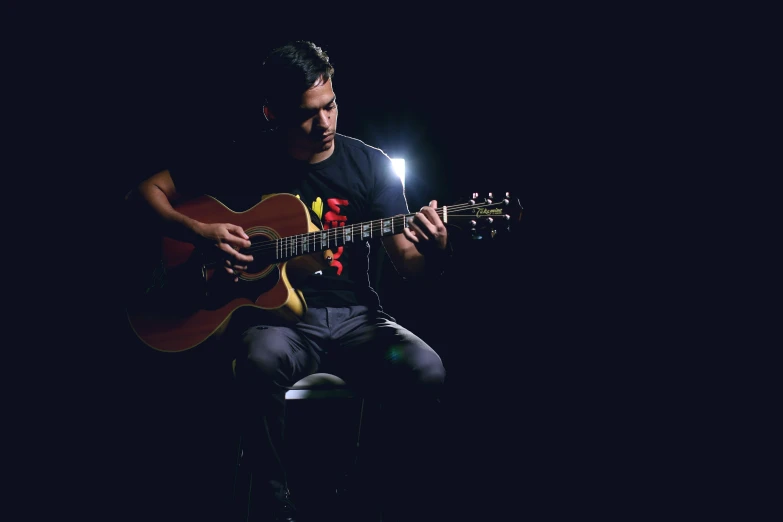 a man sitting on a stool playing a guitar, an album cover, by Alejandro Obregón, pexels contest winner, standing with a black background, 15081959 21121991 01012000 4k, brightly lit, lachlan bailey