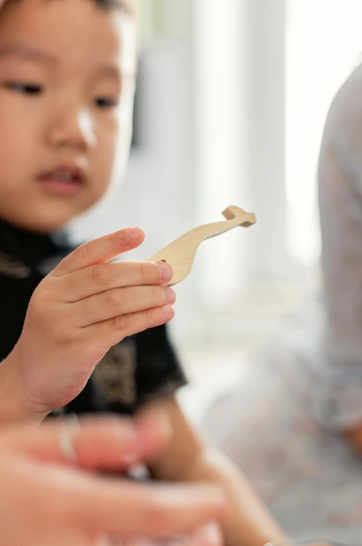 a close up of a child playing with a piece of wood, spoon placed, customers, ross tan, connectivity