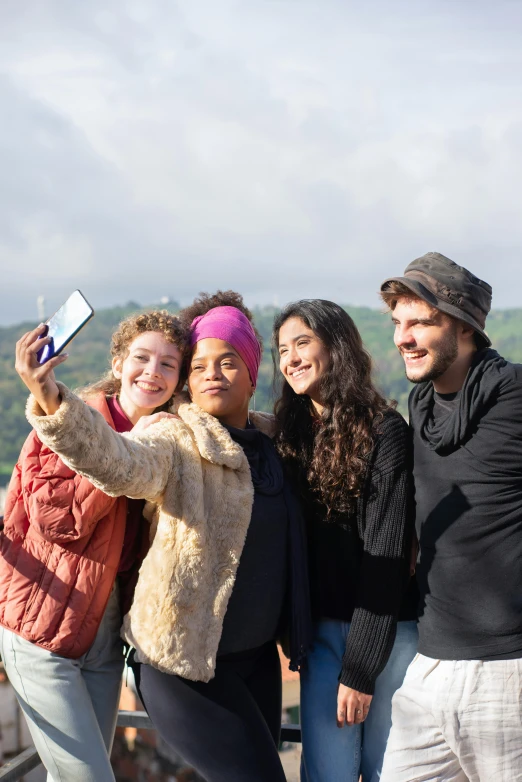 a group of people taking a picture with a cell phone, posing for camera