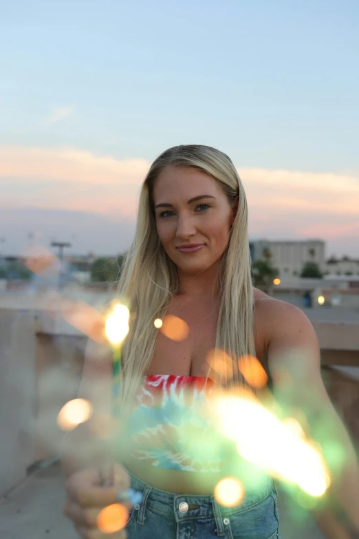 a woman standing on top of a roof holding a sparkle wand, a portrait, by Robbie Trevino, portrait of nicole aniston, golden hour 4k, off camera flash, portrait of kim petras