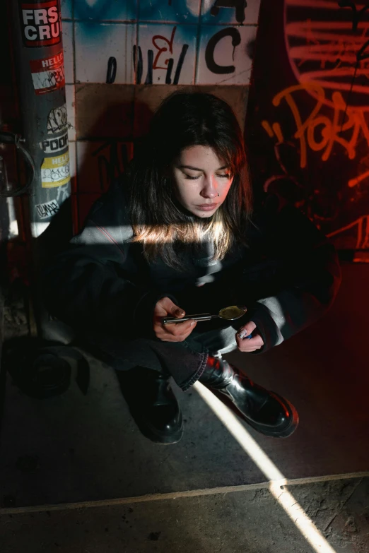 a woman sitting on the ground holding a camera, inspired by Elsa Bleda, graffiti, dua lipa, checking her cell phone, standing in a dimly lit room, artgasm