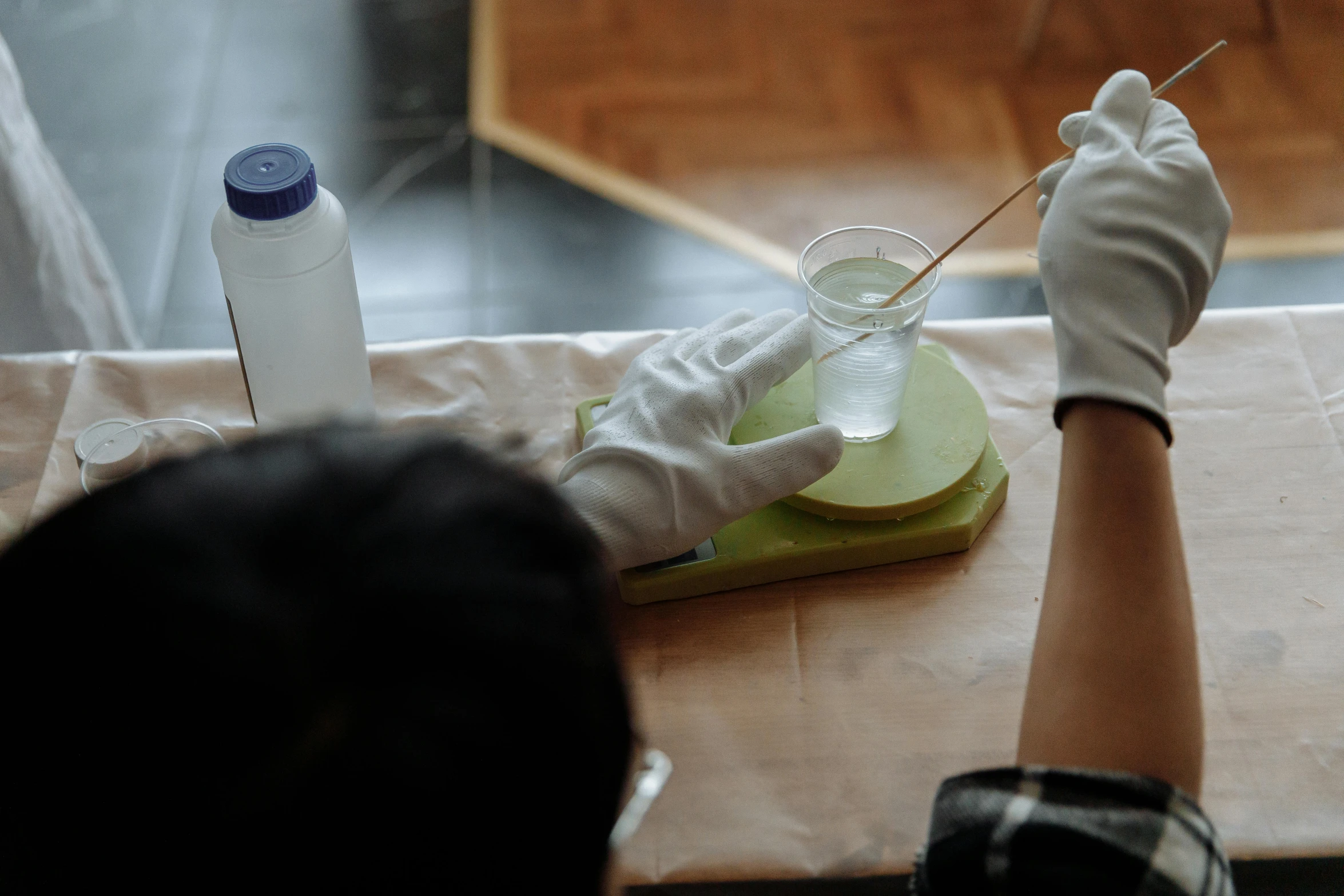 a person in white gloves sitting at a table, pexels contest winner, process art, clear liquid, lacquerware, clone laboratory, taejune kim