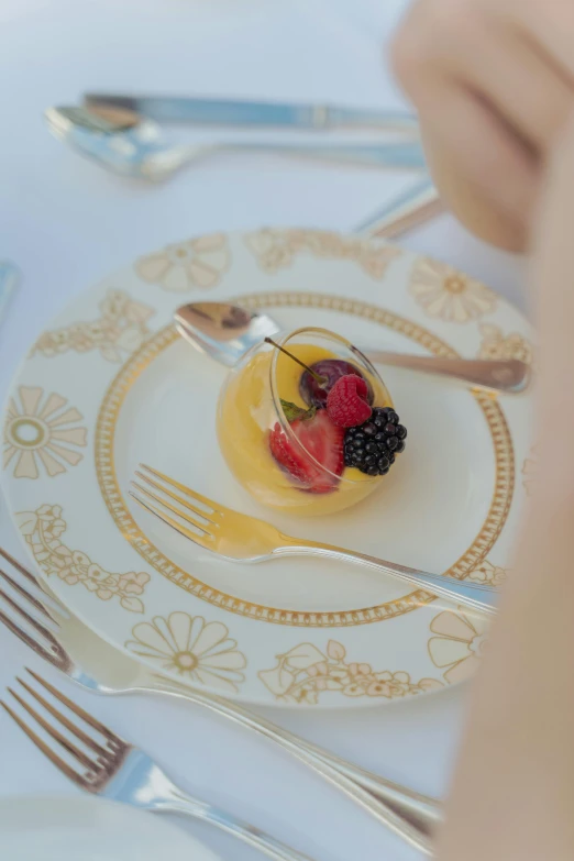 a close up of a plate of food on a table, by Lucette Barker, dessert, berries decoration on the dress, white and yellow scheme, cutlery