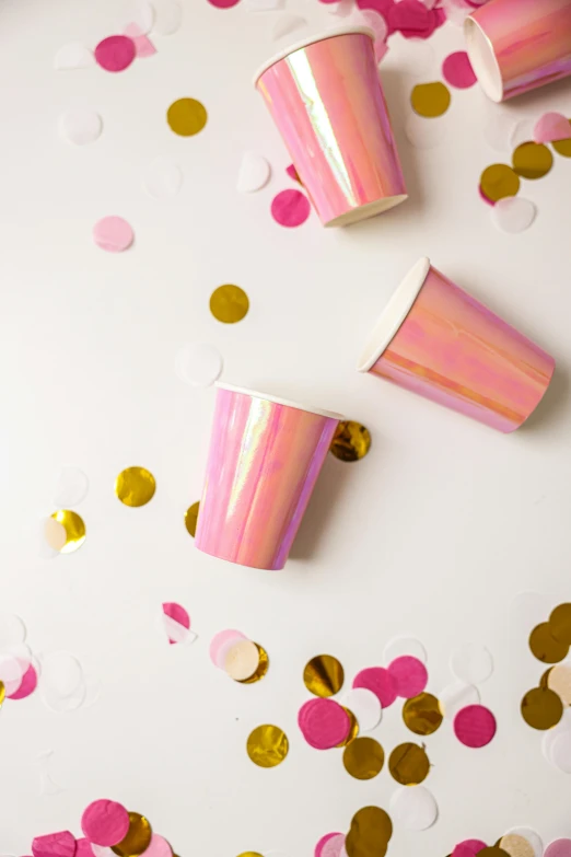 a white table topped with lots of pink and gold confetti cups, reflective gradient, product shot, ((pink)), kind