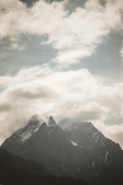 a black and white photo of a snow covered mountain, poster art, trending on unsplash, baroque, dreamy clouds, brown, patagonian