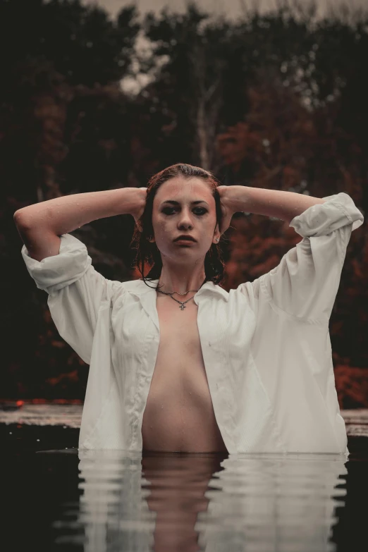 a woman standing in the water with her hands on her head, inspired by Elsa Bleda, unsplash, renaissance, open shirt, wearing a white button up shirt, androgynous vampire, fall season