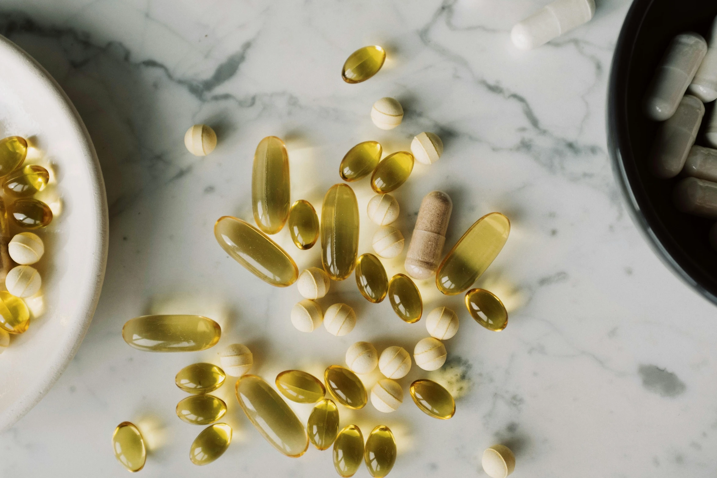 a plate of fish oil capsules next to a bowl of fish oil, by Jessie Algie, trending on pexels, renaissance, dwell, goop, sun overhead, shades of gold display naturally