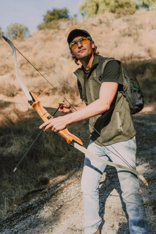 a man holding a bow and arrow on a dirt road, arcane clothing, profile image, tourist photo, profile picture