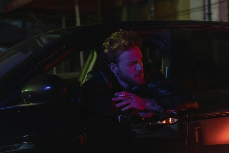 a man sitting in the passenger seat of a car, an album cover, by Elsa Bleda, photorealism, official music video, neon lights and adds, liam, attractive man