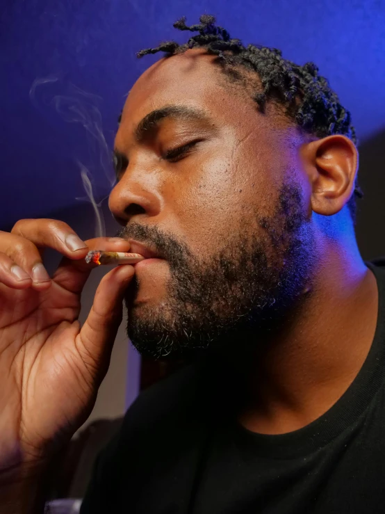 a man in a black shirt smokes a cigarette, by Stokely Webster, densely packed buds of weed, profile image, mutton chops, laying down