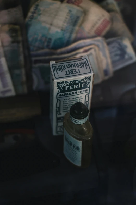 a newspaper sitting on top of a table next to a bottle of liquid, by Adam Pijnacker, pexels contest winner, 1 9 7 0 s car window closeup, 12th century apothecary shop, banknote, cinestill 800t 35mm eastmancolor